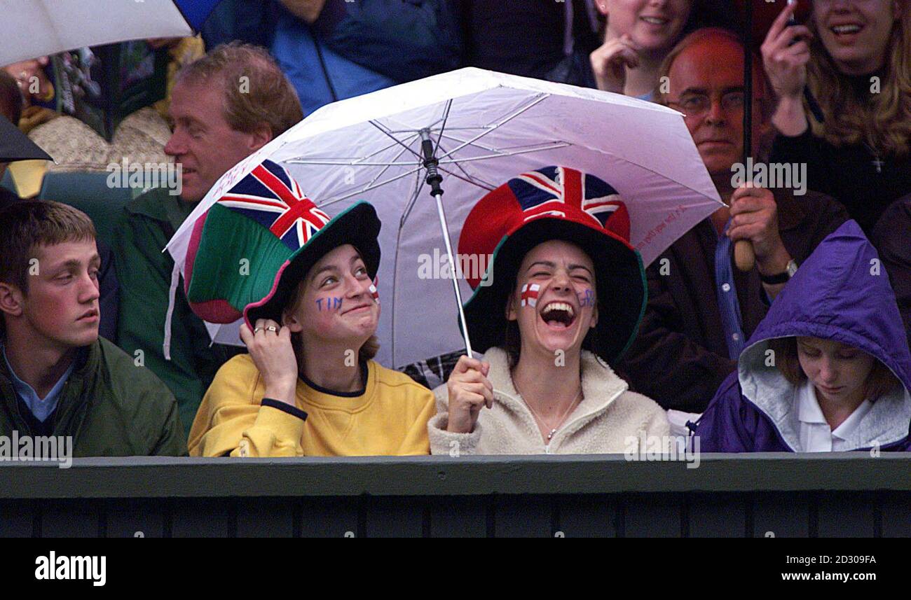 No Commercial Use: Two unnamed tennis fans enjoy themselves as the rain falls on the Centre Court at the Wimbledon Tennis Championships. Tim Henman is due to finish his match against Jim Courier when the rain stops falling. Stock Photo