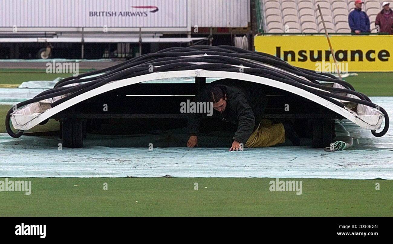 Groundstaff at Old Trafford check the state of the pitch, which has been under cover all night, as heavy overnight rain delayed  the start of the final day's play in Manchester, where England are playing New Zealand in the Third Test. Stock Photo