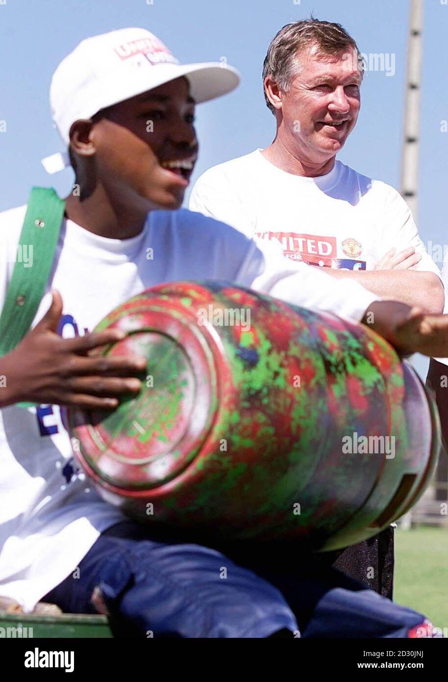 This picture can only be used within the context of an editorial feature. Manchester United manager Sir Alex Ferguson (R) watches as his football team are entertained by steel-pan drummers from Unicef, sponsored by a project in Rio de Janeiro, Brazil. Stock Photo