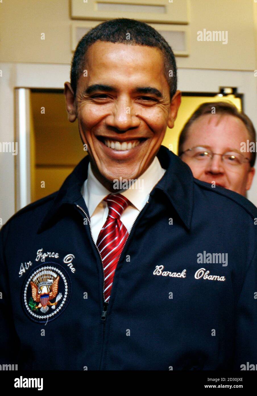 U.S. President Barack Obama sports his new Air Force jacket with his name  upon it as he speaks to reporters during his first flight aboard Air Force  One February 5, 2009. Obama