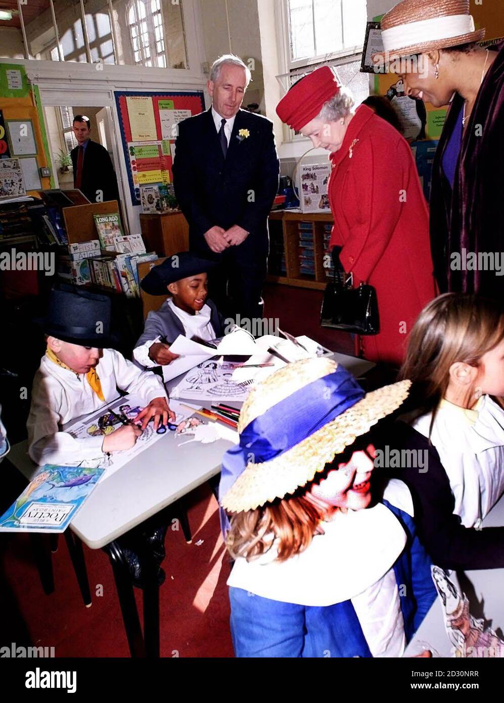 Queen Elizabeth II looks at children dressed up in Victorian clothes, during her visit to to the Clerkenwell Parochial School in London. Stock Photo