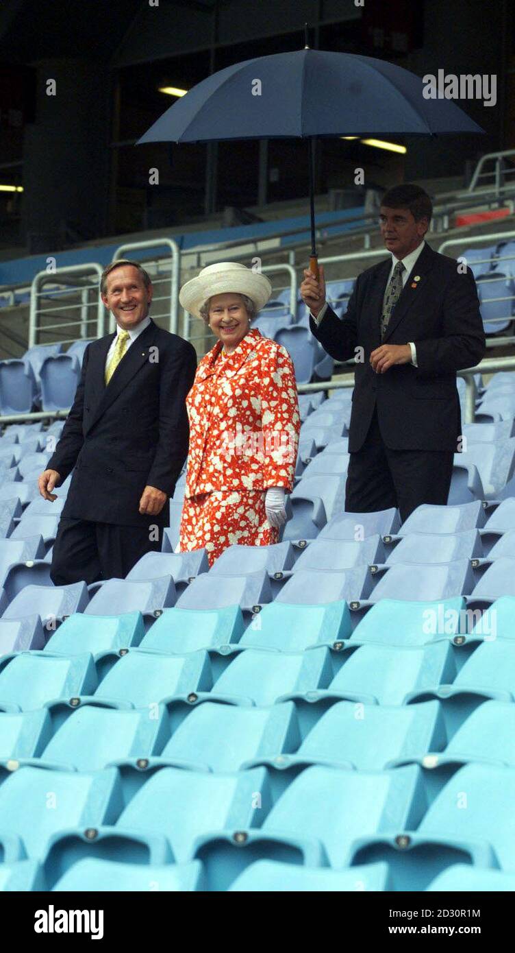 The Queen inspects Stadium Australia at Homebush Bay in Sydney Australia, with Bob Leece (left) Deputy Director General of the Olympic Co-ordination Aurthority as a security man holds an umbrella. Stock Photo