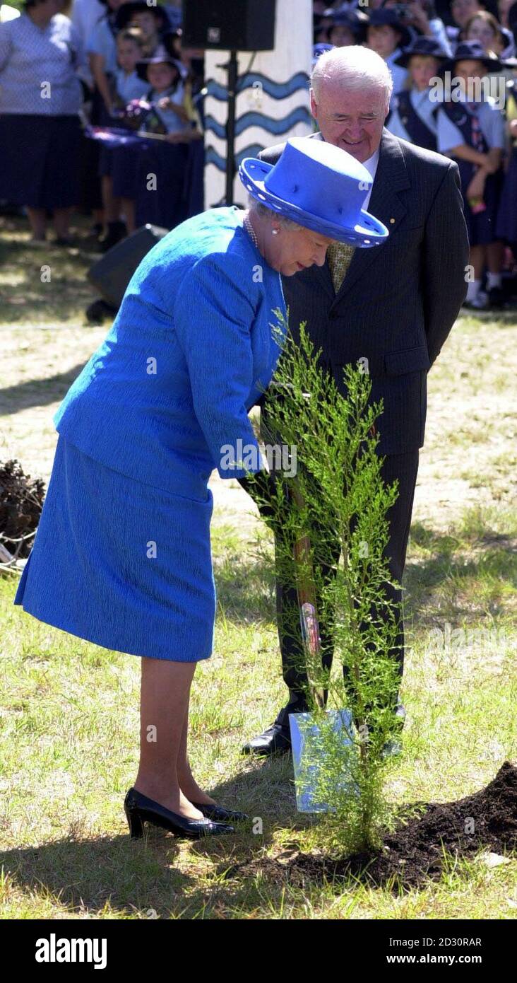 Britain's Queen Elizabeth II plants a tree in the grounds of the Australian Centre for Christianity and Culture in Canberra, accompanied by Sir William Deane, the Governor General of Australia.  Stock Photo