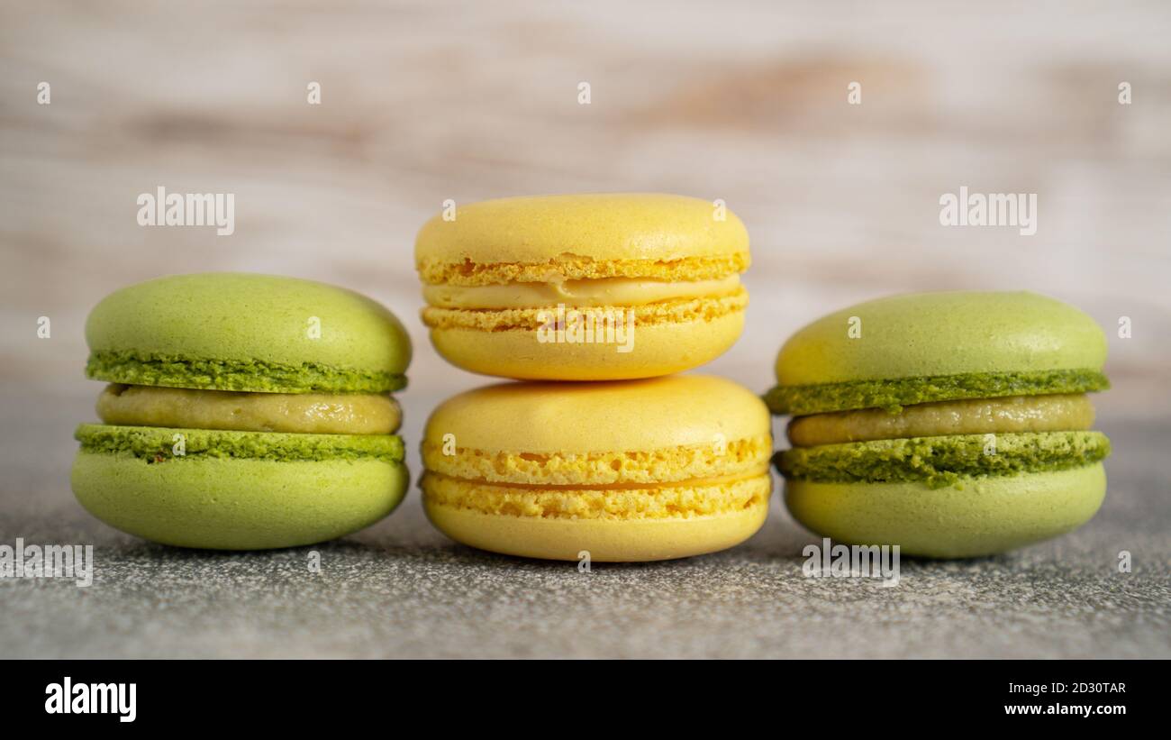 Close up of tasty stacked yellow and green macaroon cakes on grey table. Pistachio and lemon french macaroons. High quality photo Stock Photo