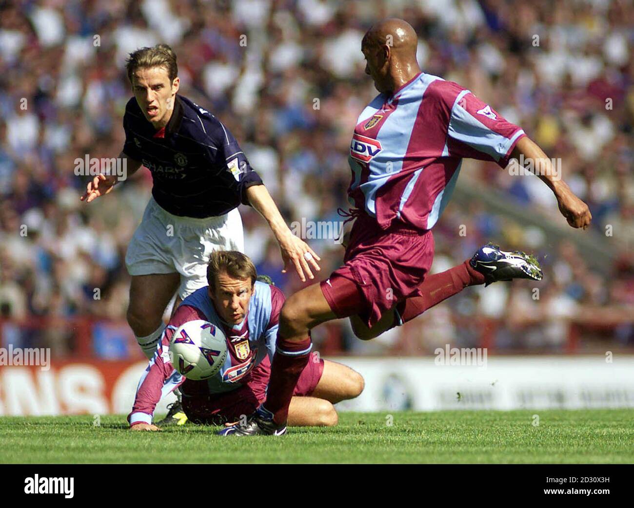 This picture can only be used within the context of an editorial feature. Aston Villa's Dion Dublin lines up his shot under the eyes of Manchester United's Phil Neville and Villa's Paul Merson during the FA Carling Premiership football match at Villa Park, Birmingham. Stock Photo