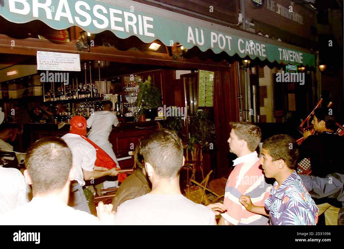 A Turkish soccer fan throws a chair through a bar window (R) after their victory against Belgium in the Euro 2000 championships in Brussels. They went on a violent rampage of the city, smashing bars and hunting for English fans to attack. Stock Photo