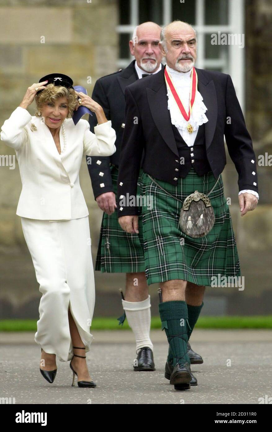 Actor Sir Sean Connery, with wife Micheline, and brother Neil Connery, donning full Highland dress and wearing his medal after he was formally knighted by the Queen during a investiture ceremony at the Palace of Holyroodhouse in Edinburgh. * Connery knelt while the Queen touched his shoulders lightly with a sword and made him a Knight in the Palace's Picture Gallery. Stock Photo