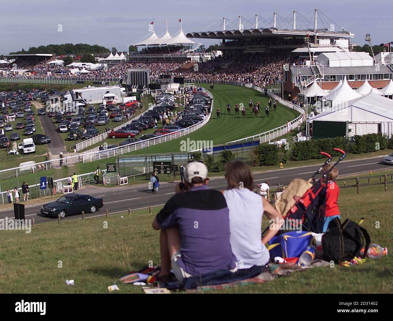 Race fans get a free view of the Goodwood racecourse from Trundle Hill  on the first of five days racing festival at the West Sussex track.  Stock Photo