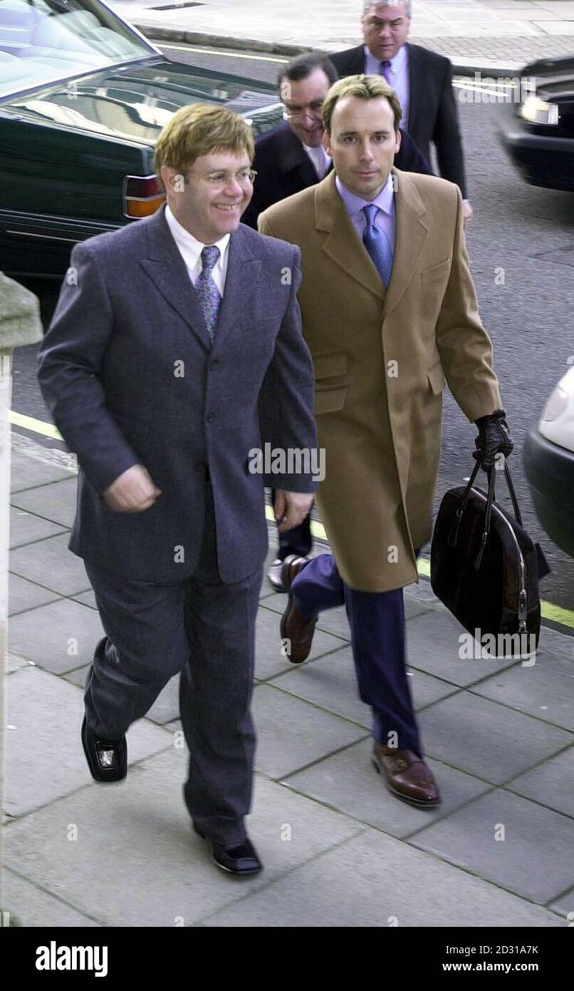 Pop star Sir Elton John, with his partner David Furnish, returning to the High Court in London after lunch. Earlier he was giving evidence in his multi-million pound contract battle.   *Sir Elton today agreed in the High Court that he and his former manager John Reid both enjoyed a somewhat lavish lifestyle and had helped each other with personal problems over drink and drugs. Stock Photo