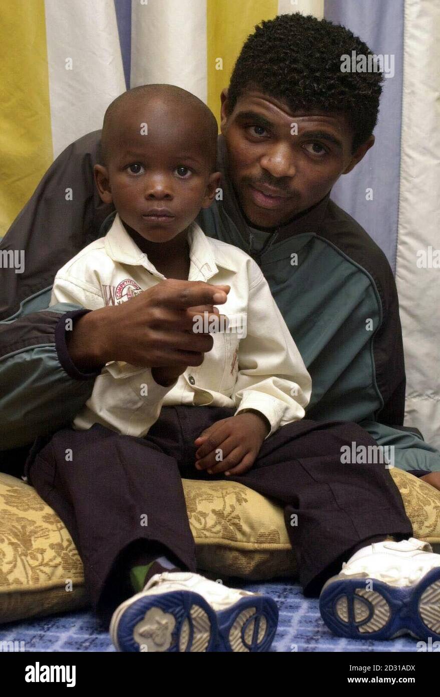 Arsenal soccer star Nwankwo Kanu meets four-year-old Tofunmi Okude during a press conference in London. Tofunmi was flown over from Nigeria for a livesaving heart operation, made possible through Kanu's Heart Foundation. Stock Photo