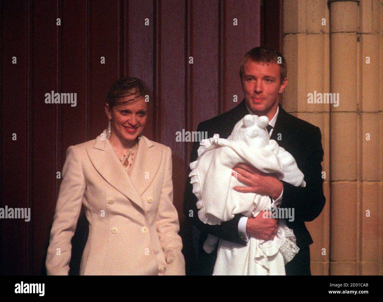 American singer Madonna and British film director Guy Ritchie with their four-month-old baby son Rocco, wrapped in a white christening gown, after the baby was christened at Dornoch Cathedral in Sutherland, Scotland.  * 29/3/01: A man who hid behind a cathedral organ to secretly film the star-studded christening service for Madonna's baby was appearing at court for sentence. At a previous hearing at Dornoch Sheriff Court, Sheriff Ian Cameron called for Robert Podesta to appear in person to give a full picture of his financial circumstances before sentencing.    Stock Photo