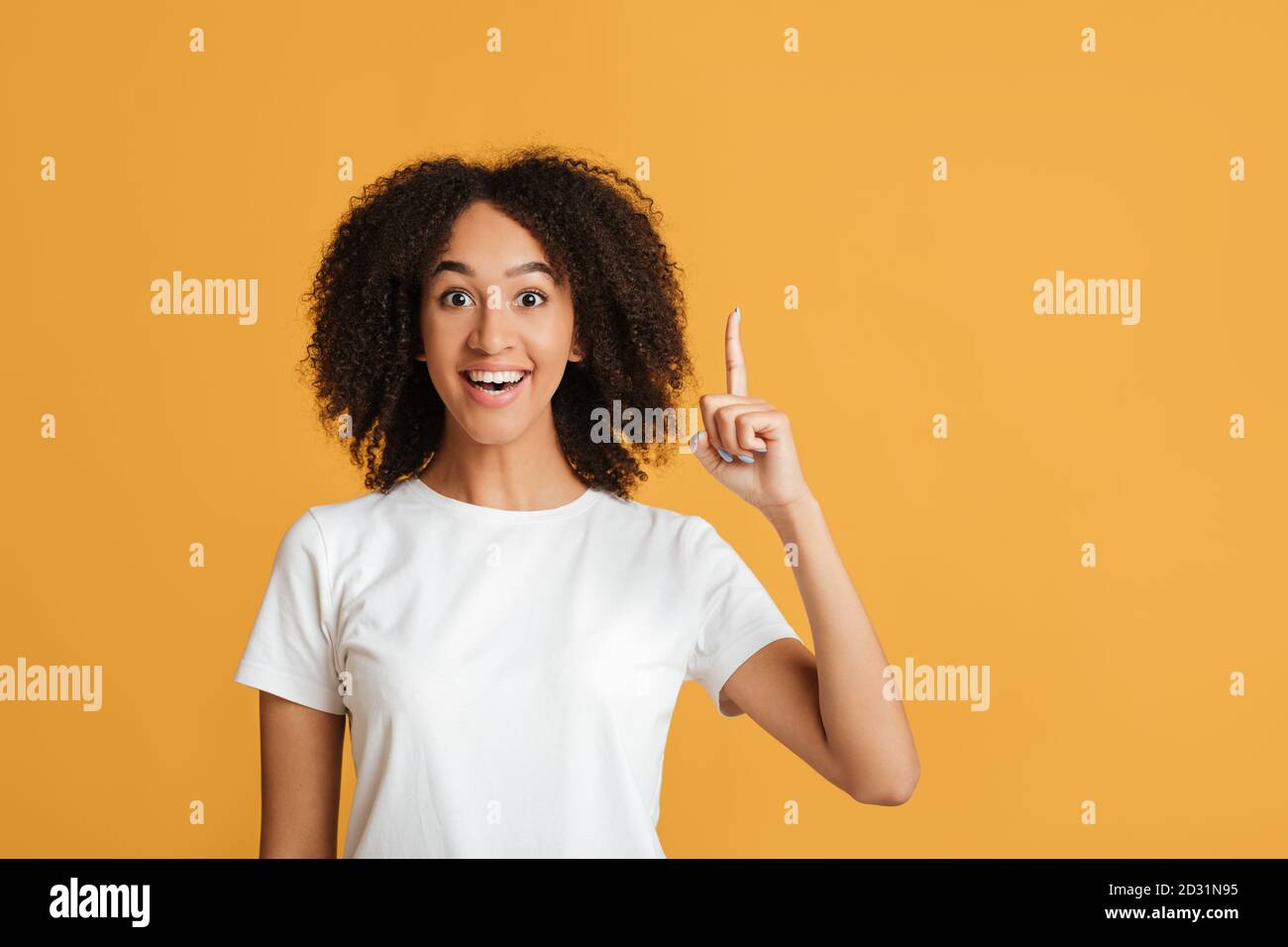 Great idea and good mood. Young smart african american woman wears casual with open mouth pointing finger up at free space and has successful plan Stock Photo