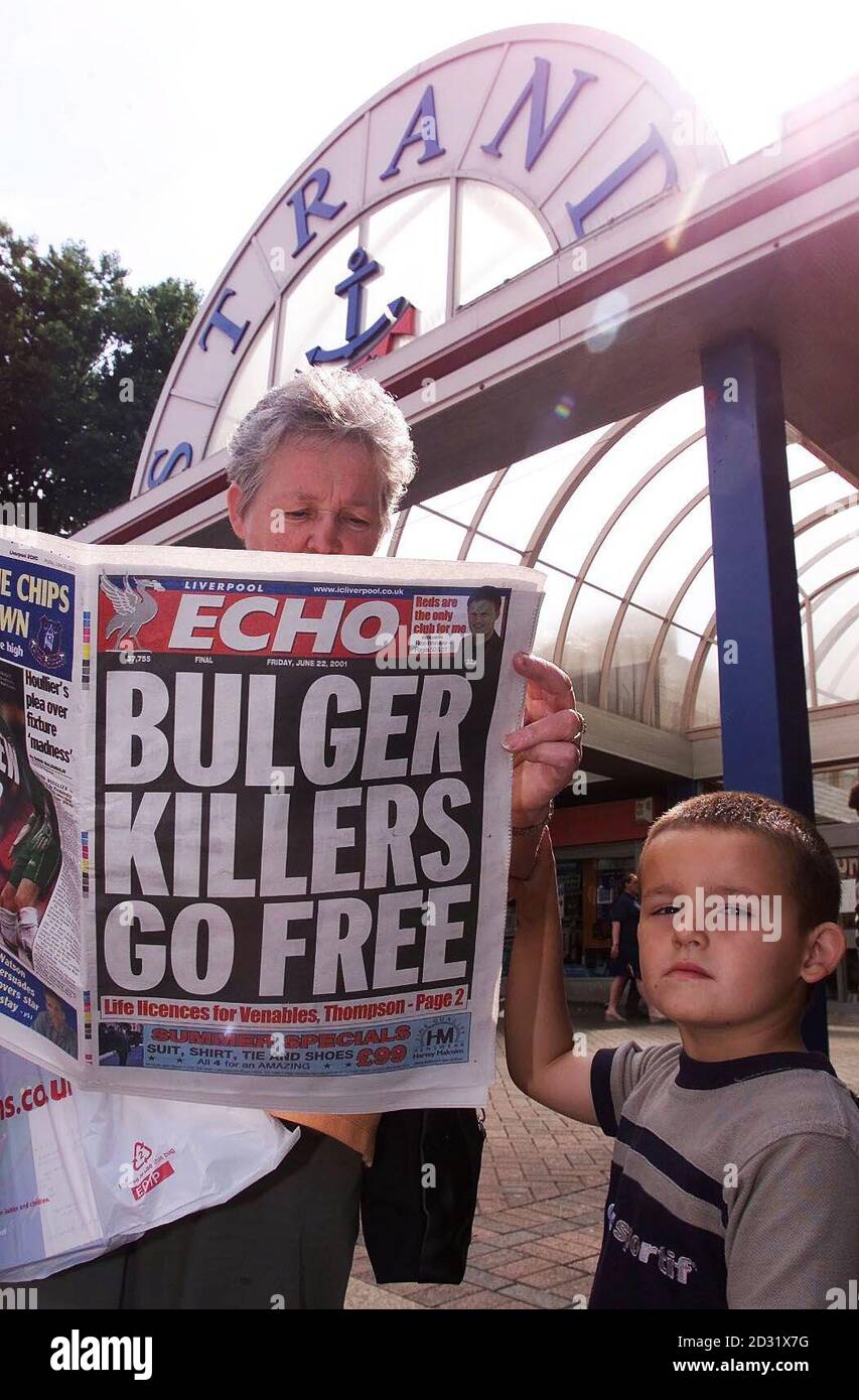 Barbara McHugh and her grandson Alex aged 4, read about the release of the killers of James Bulger in the local paper outside the Strand shopping centre in Bootle, from where James was abducted by Venables and Thompson. Stock Photo