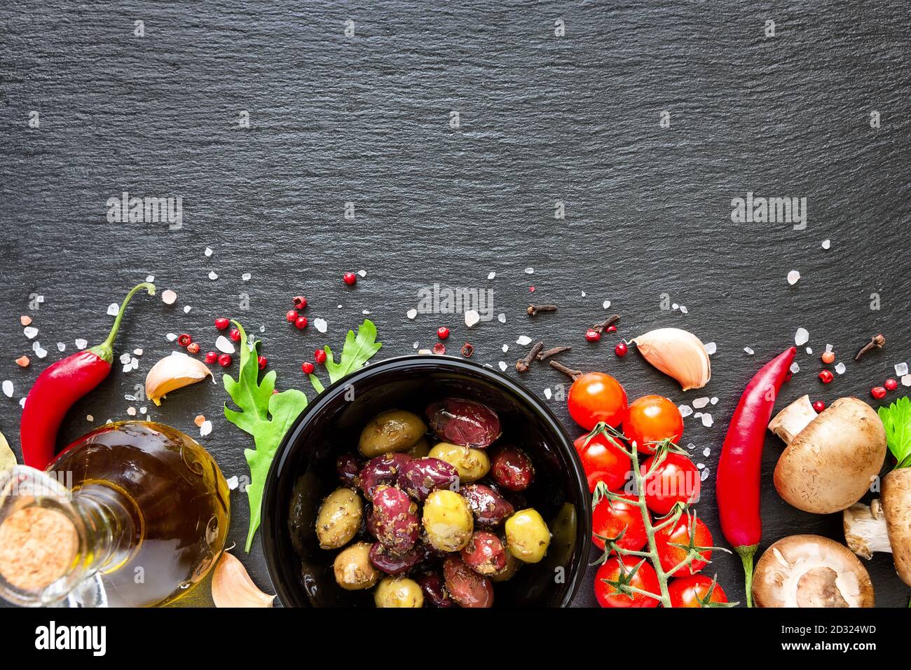 Food ingredients on dark background. Tomatoes, spices, garlic, mushrooms and basil leaves on black background. Vegetarian food, health or cooking conc Stock Photo