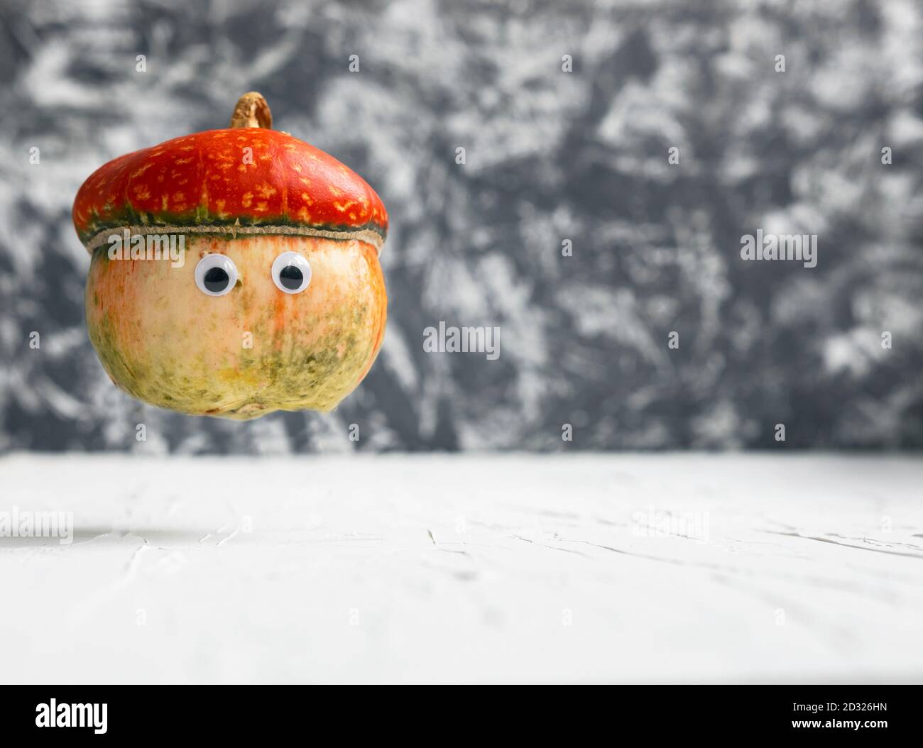Closeup Photo of Funny small flying pumpkin with eyes on white and grey background, Copy space, halloween concept Stock Photo