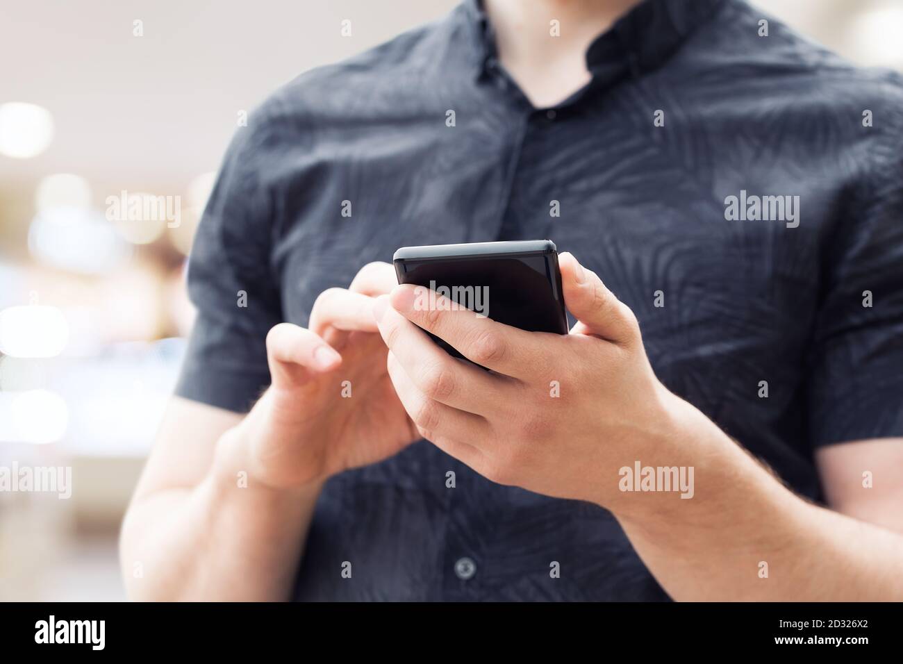 Man using mobile smart phone, close up. Picture of young man using a mobile smart phone and smiling. Stock Photo