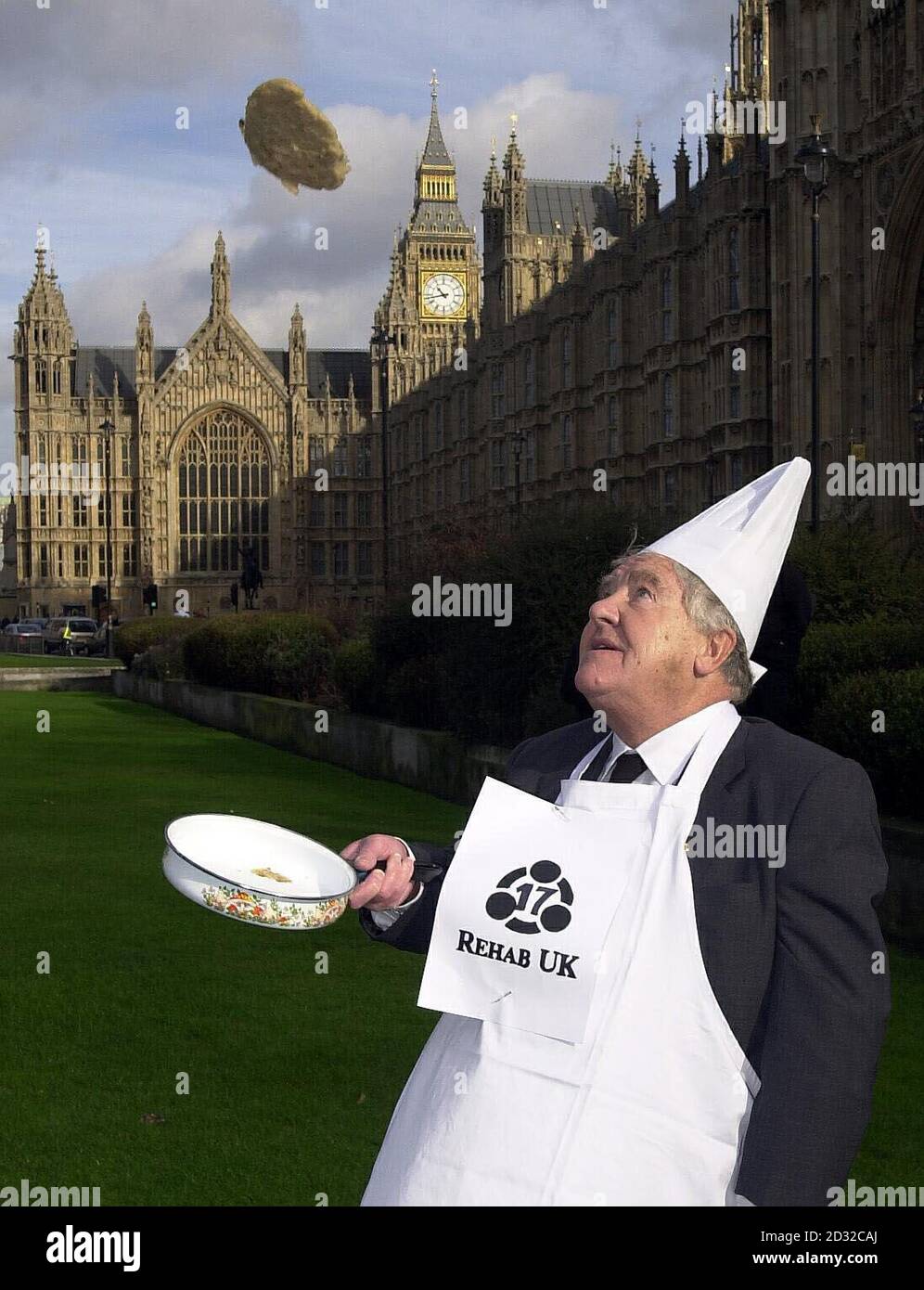 Lord Morris of Manchester, takes part in the annual Shrove Tuesday Parliamentary pancake race on the green opposite the House of Lords in Westminster, London. The event, in aid of brain injury charity Rehab UK, involves a team of MPs and a team from the Lords,  *   donning tall chefs' hats and whites and racing each other while tossing pancakes three feet into the air. Stock Photo