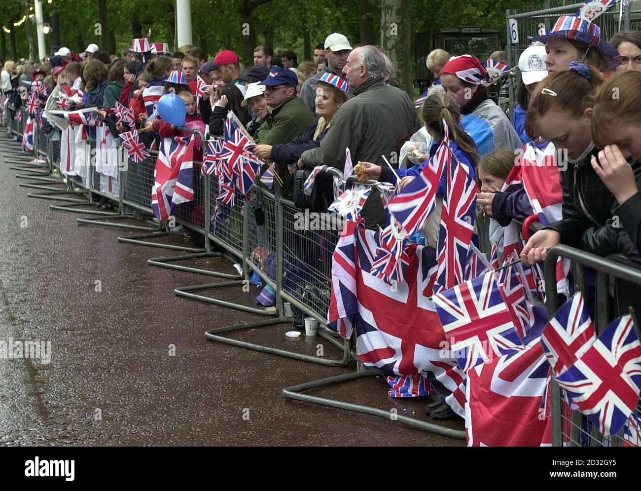 Early morning spectators holding their Union Jack flags waiting to see Britain's Queen Elizabeth II outside Buckingham Palace. The Queen and the Duke of Edinburgh will leave Buckingham Palace in a State Gold Coach for a thanksgiving service at St Paul's Cathedral. * ...  before returning to watch a parade in The Mall on the final day of the Golden Jubilee Bank Holiday weekend. Stock Photo