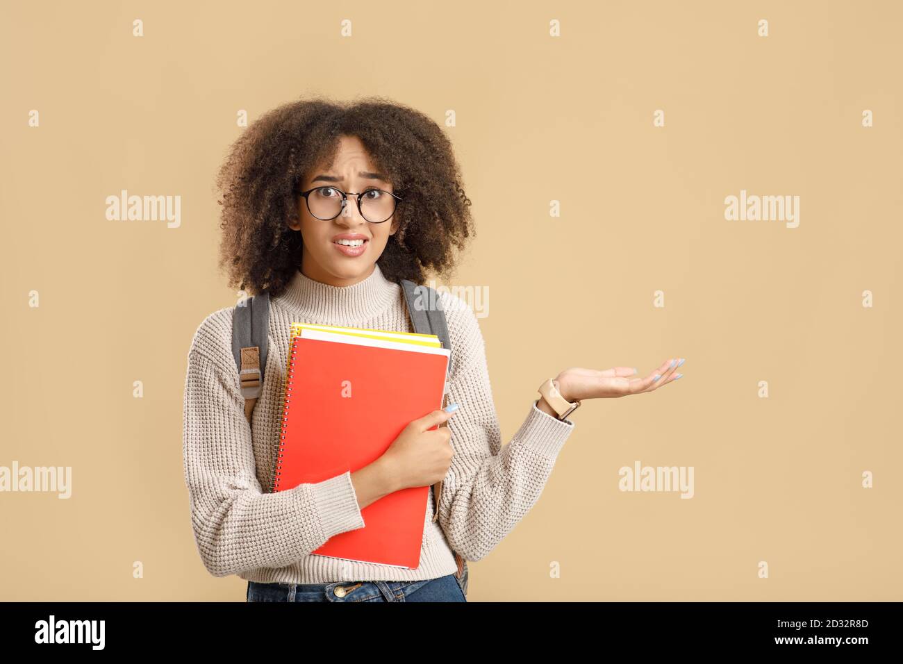 Negative human emotions, unpleasant or wrong choice. Doubting african american woman in glasses and notepads points hand to free space Stock Photo