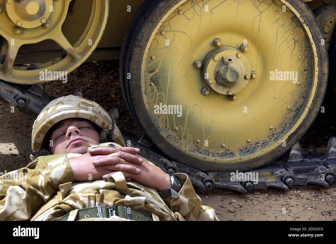 An exhausted Scimitar commander of the Household Cavalry regiment catching up on his sleep in the shade of his tank. Stock Photo
