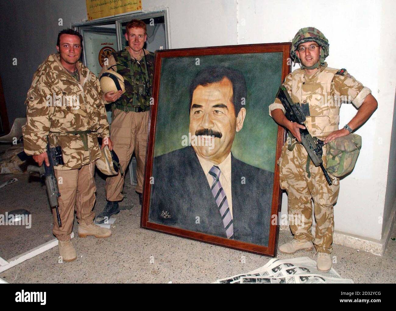 (L-R) Capt Joe Power, Maj Andrew Britton and Capt Simon Ridgway stand near the picture of Saddam in the foyer at the Ba-ath party headquarters at Basra as Cyclops squadron from the 2nd Royal Tank Regiment take the town in southern Iraq. Stock Photo