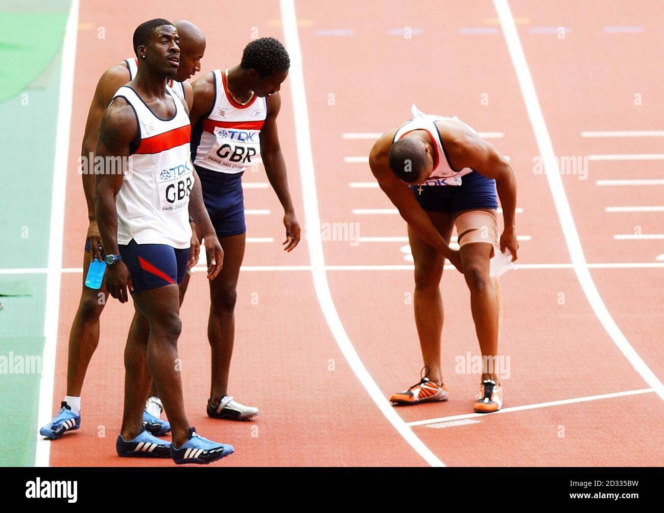 The GB 4x100 relay team (from l-r), Dwain Chambers, Marlon Devonish and Christian Malcolm look on, as team-mate Darren Campbell (far right) wraps up his injured leg after finishing second behind the USA team in the men's 4x100 relay final at the Athletics World Championships in Paris. Stock Photo