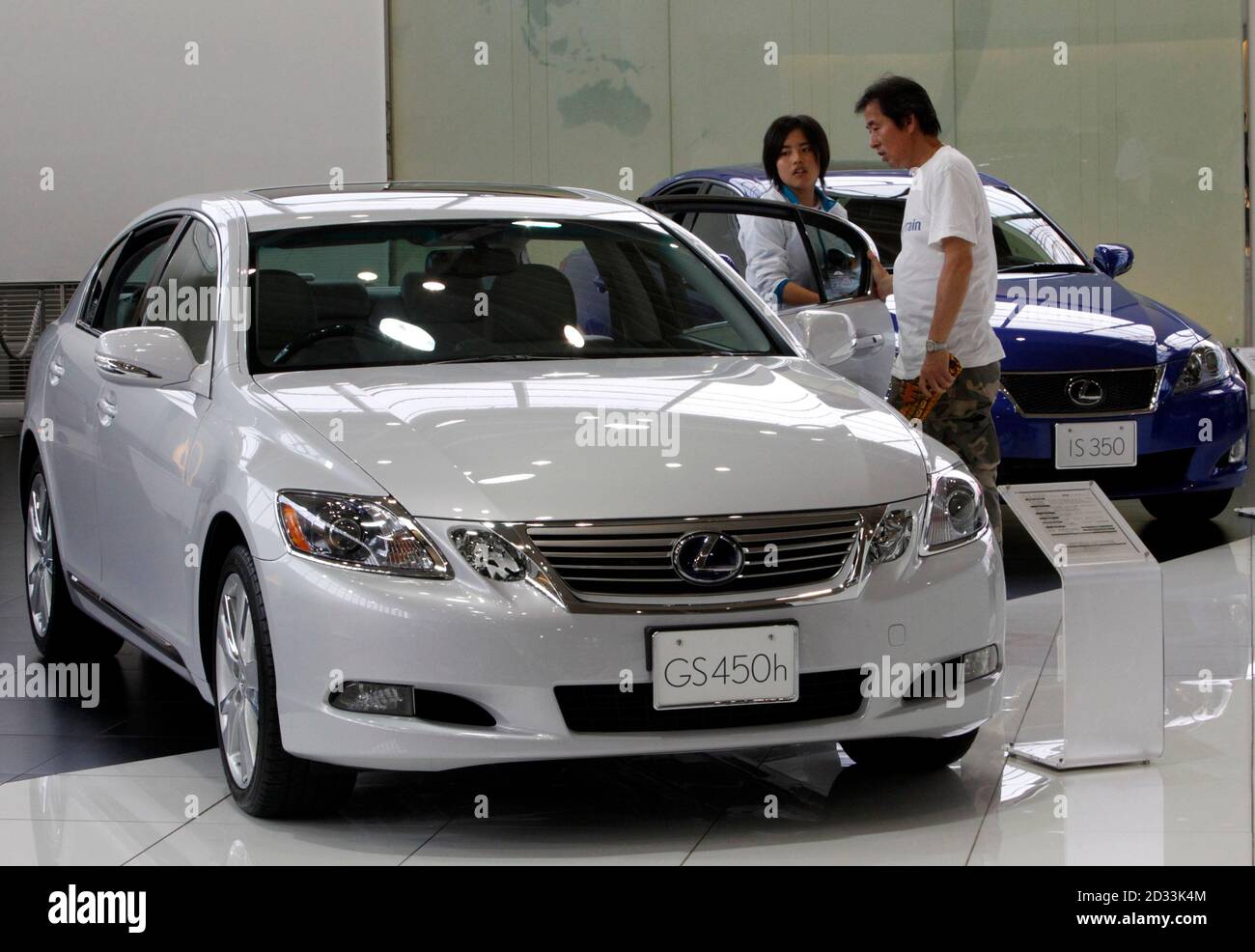 People look at a Toyota Motor's Lexus GS 450h model as a Lexus IS 350 model  is displayed beside it at a showroom in Tokyo July 4, 2010. Toyota Motor  Corp said