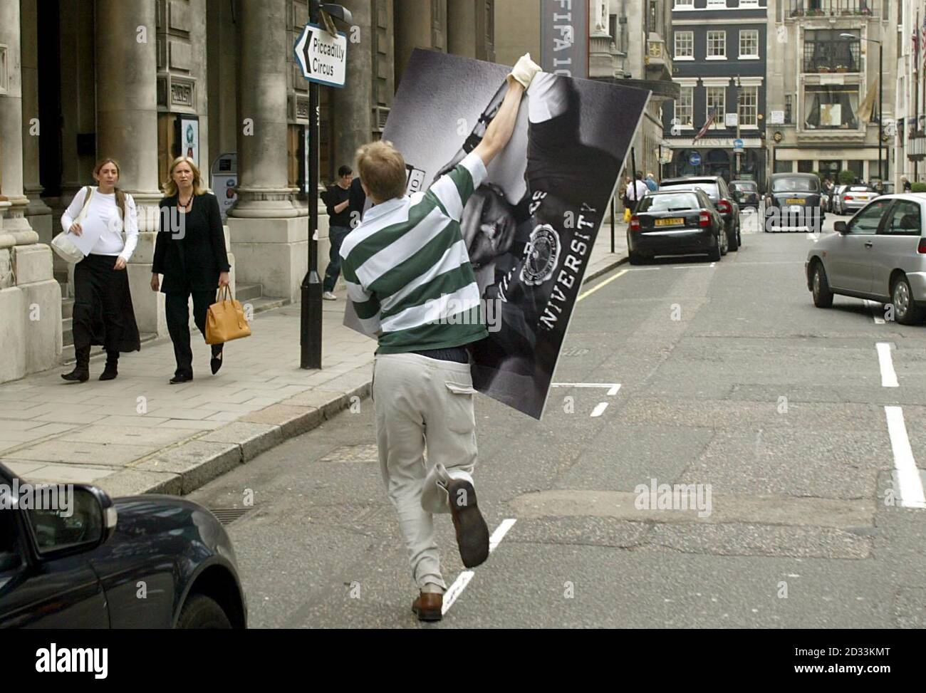 A Fifa gallery attendent heads back at speed after spotting press, having left through the back door of the Fifa Exhibition at the Royal Academy of Arts, London. He is carrying a picture of the England Captain David Beckham which was defaced with the words 'You Losers', written in red marker pen across his face. Stock Photo