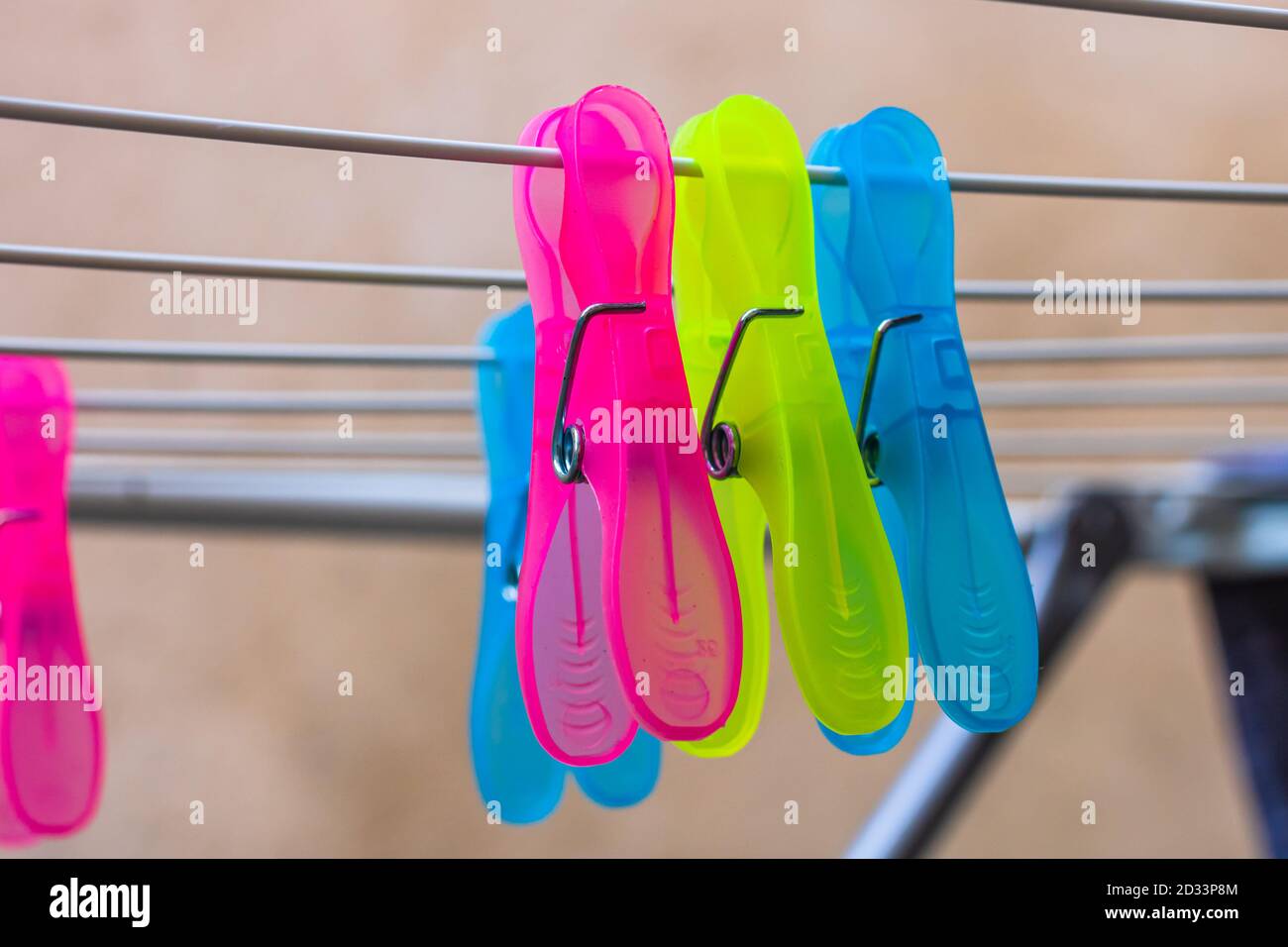 Colorful plastic clothes pegs on empty metal clothes dryer. Stock Photo