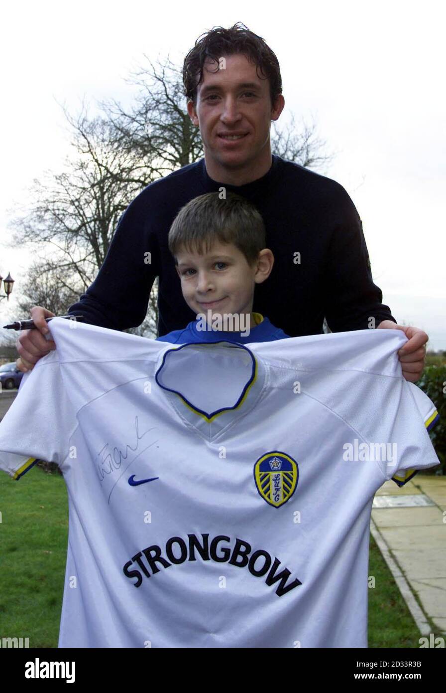 Leeds United's new signing Robbie Fowler holds up a signed shirt for eight  year old Leeds United fan Ashley Coffey (front) from Morley after the press  conference at Thorp Arch, Leeds. Robbie