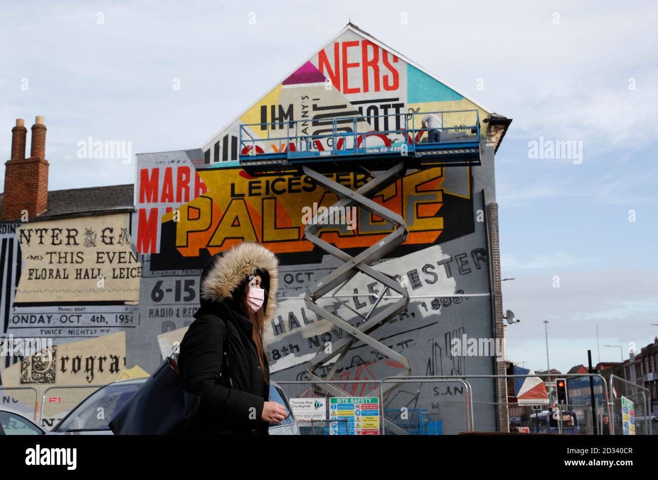 Leicester, Leicestershire, UK. 7th October 2020. A woman passes an artist working on a street mural 100 days since the UKÕs first local coronavirus pandemic lockdown was announced in the city. Credit Darren Staples/Alamy Live News. Stock Photo
