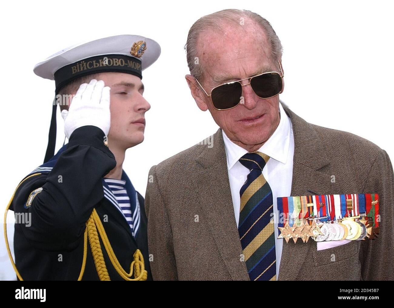 The Duke of Edinburgh wearing large sunglasses to hide a black eye, walks past a Ukrainian Naval officer at a memorial service for those who lost their lives in The Battle of Balaclava, on the 150th anniversary of The Charge of The Light Brigade, Crimea, Ukraine. Stock Photo