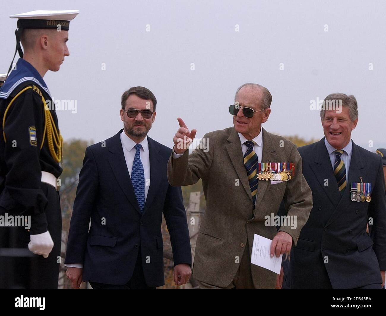 The Duke of Edinburgh wearing large sunglasses to hide a black eye, walks past a Ukrainian Naval officer at a memorial service for those who lost their lives in The Battle of Balaclava, on the 150th anniversary of The Charge of The Light Brigade, Crimea, Ukraine. Stock Photo