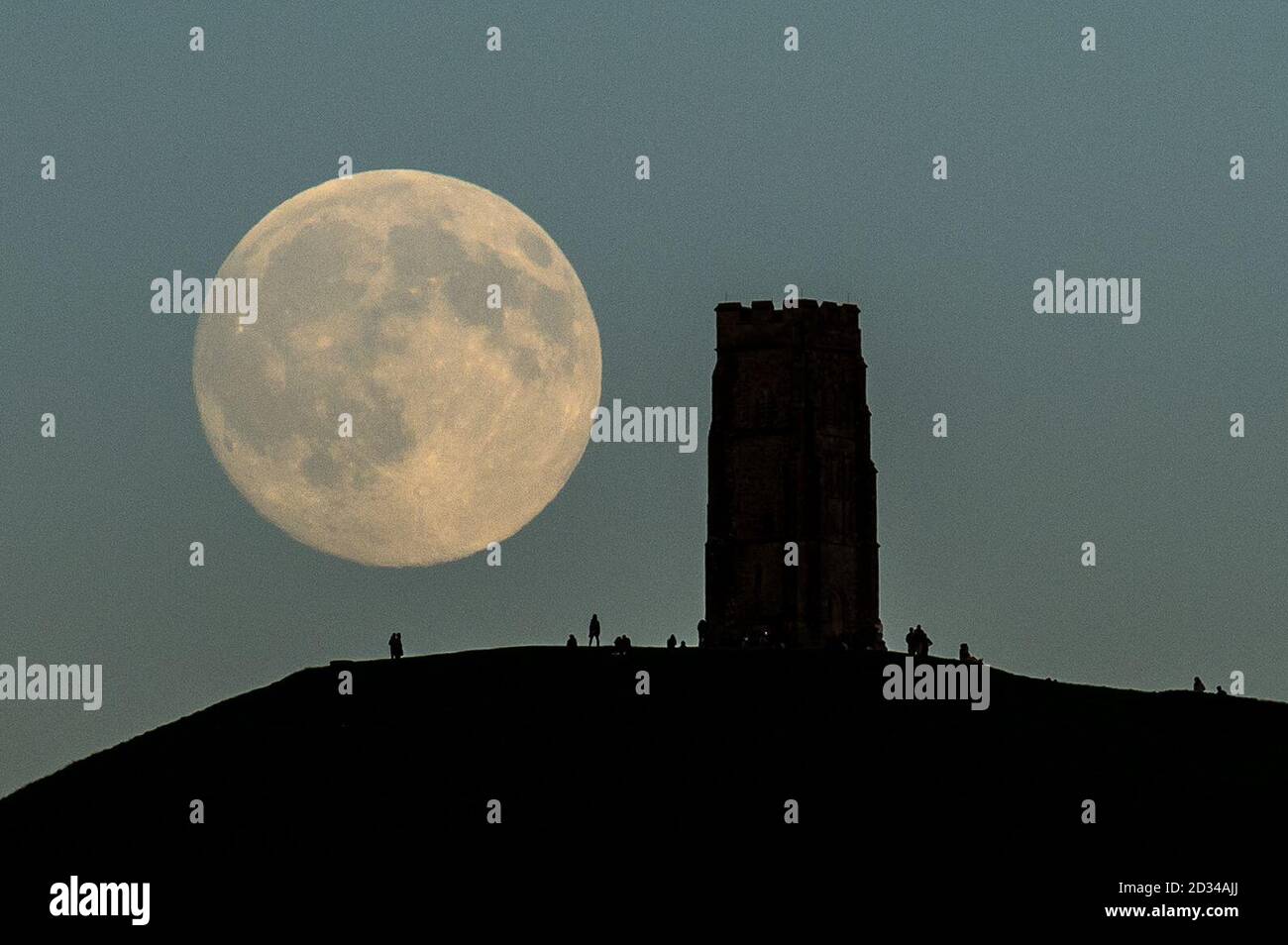The moon rises over Glastonbury Tor, Somerset, as people gather in anticipation of Friday's 'Blue Moon'. Stock Photo