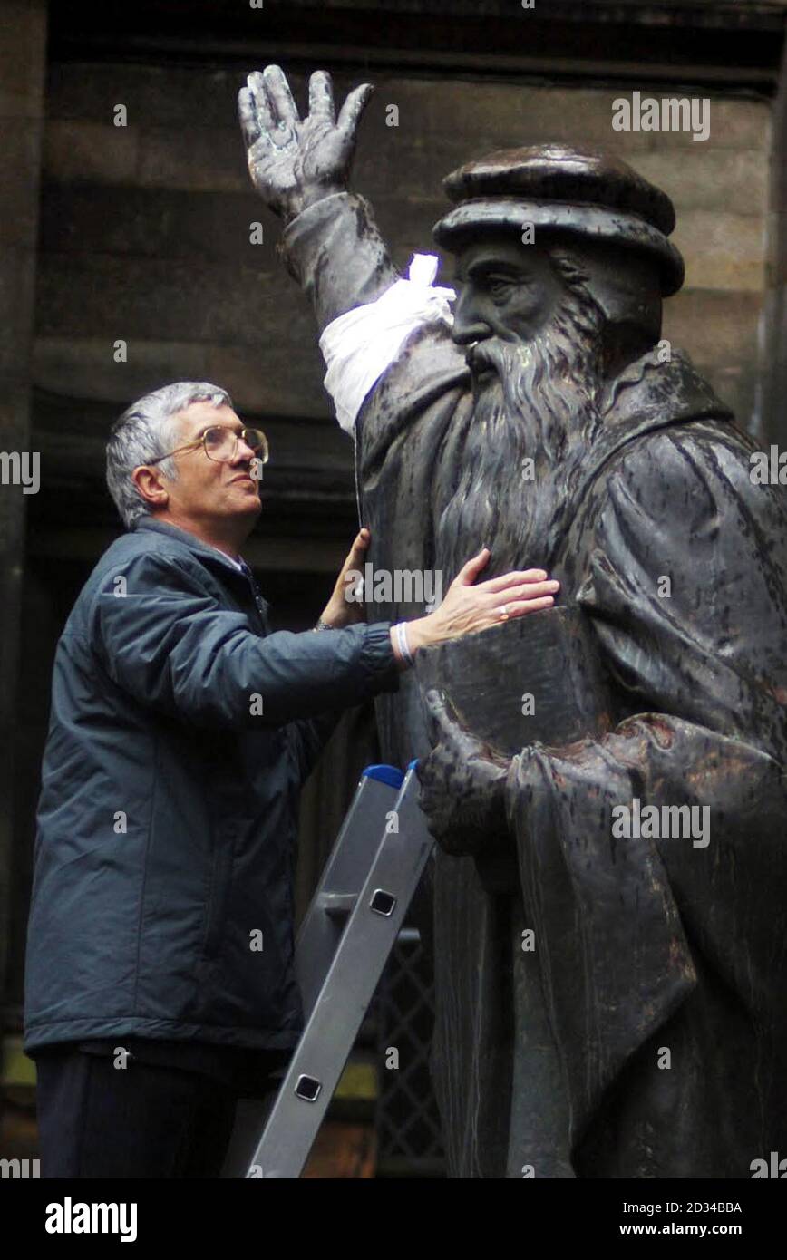 Rev Alan Greig from the Board of world Mission puts on a Make Poverty History band on the statue of John Knox. Stock Photo