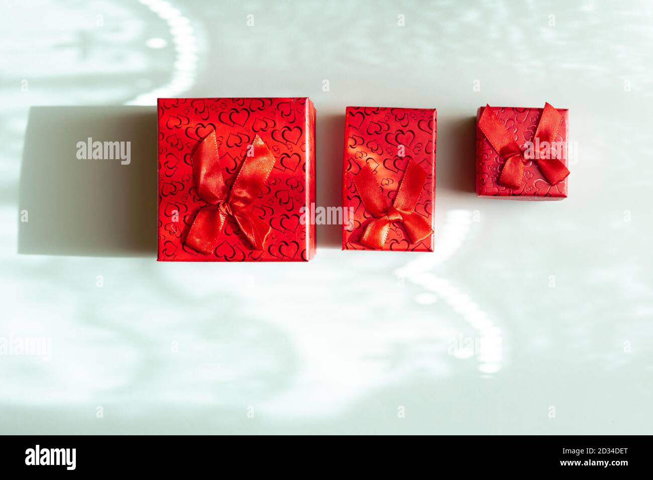 Three red gift boxes in different sizes isolated on blue background Stock Photo