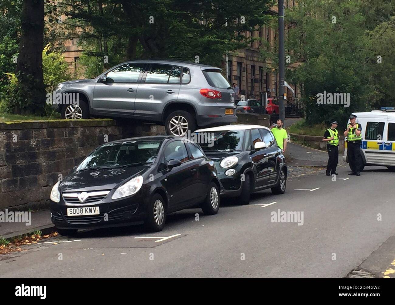 A Volkswagen on top of a Fiat 500 after the car rolled backwards down a