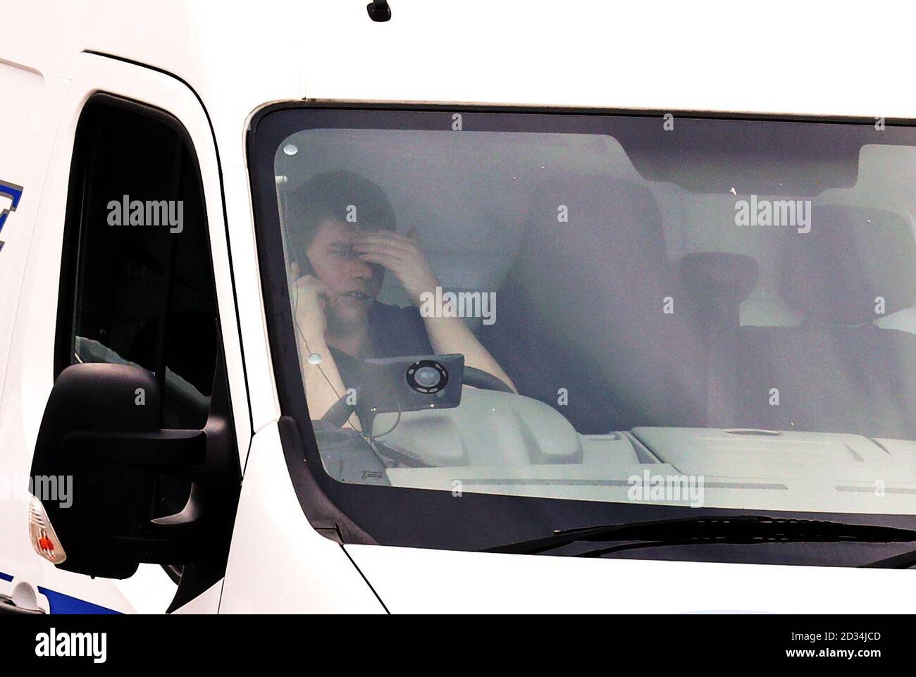 A van driver holding a mobile phone whilst driving on the M20 near Ashford, Kent. Stock Photo