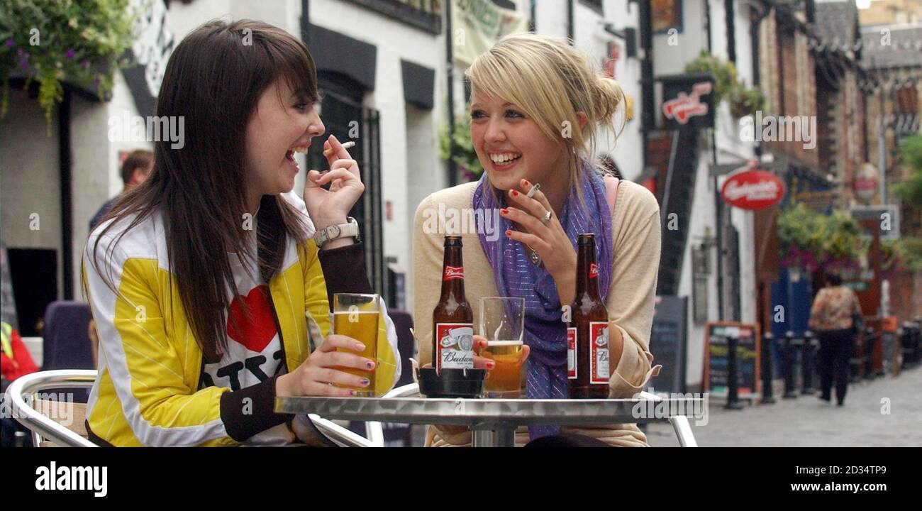 Posed photograph of Carina McGuire, 18 (left) and Anna Galbrait, 18, smoking outside the bars on Ashton Lane in Glasgow. Drink sales have dropped by more than 10% since the ban on smoking in public places came into effect in Scotland, pub bosses said today. Stock Photo