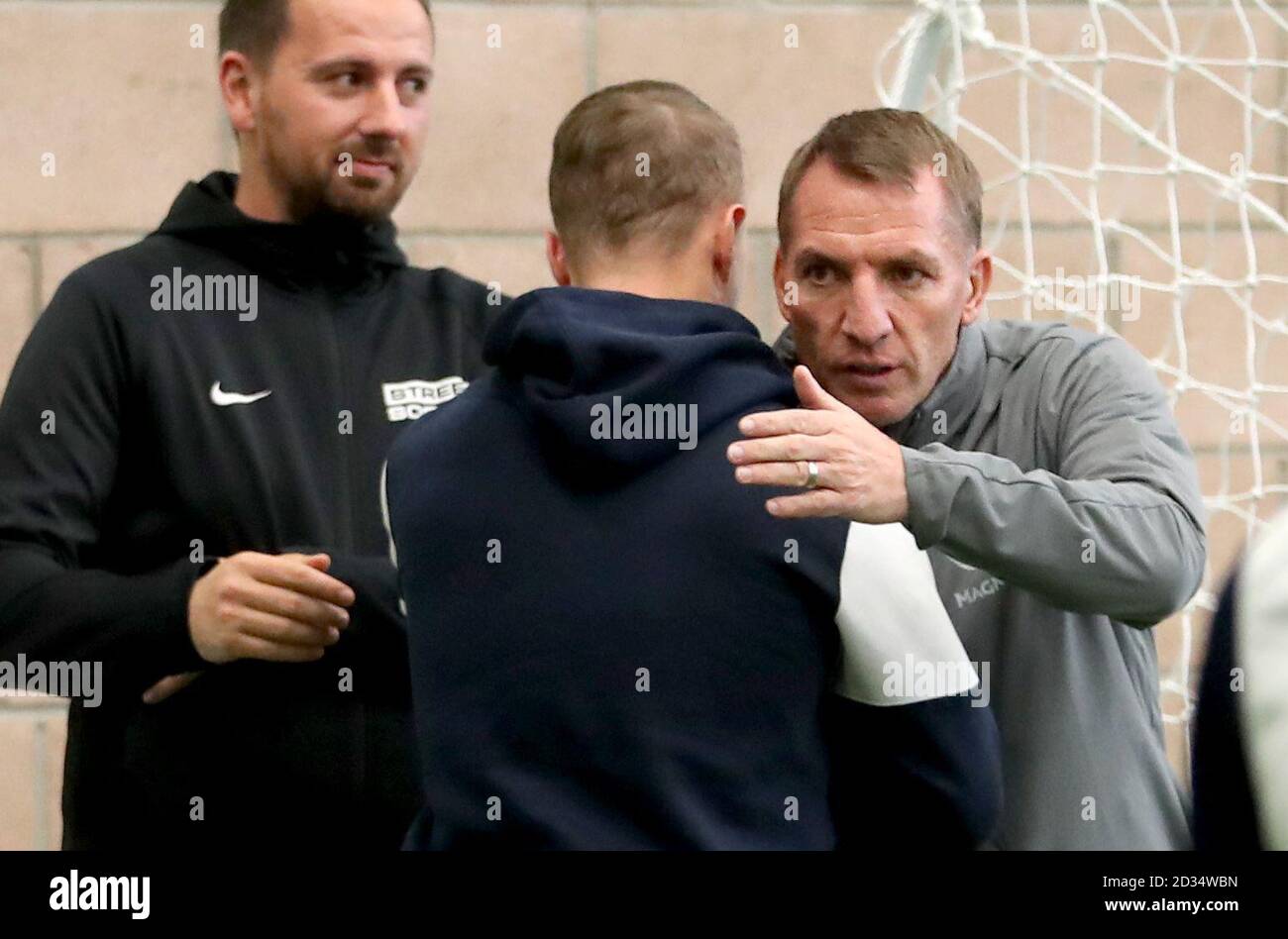 Celtic's Leigh Griffiths (centre) is hugged by manager Brendan Rodgers (right) alongside Street Soccer founder and CEO David Duke (left) as the men and women Street Soccer teams take part in a special training session at Lennoxtown, Glasgow. Stock Photo