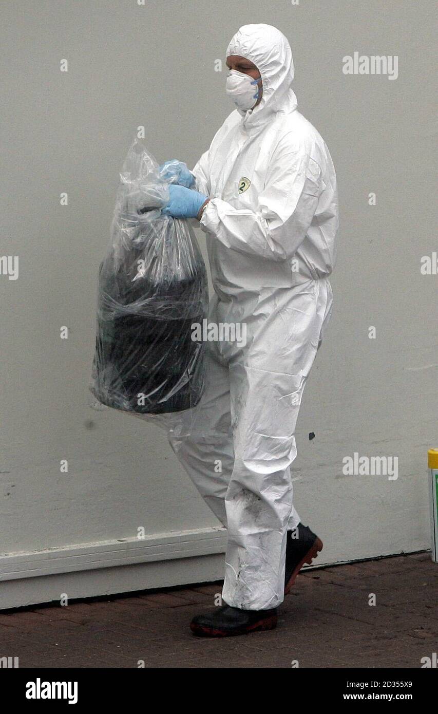 A forensic officer carries a gas canister wrapped in plastic from the scene of yesterday's