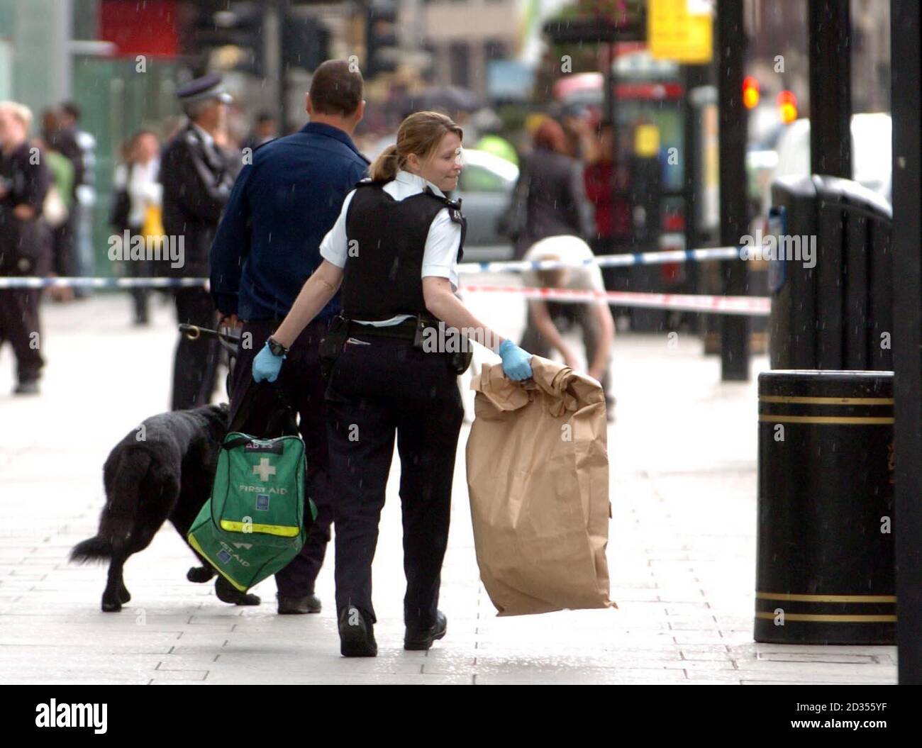 An officer removes articles from the scene outside Lloyds TSB bank on Victoria Street, London, after a Police Community Support Officer was stabbed. Stock Photo