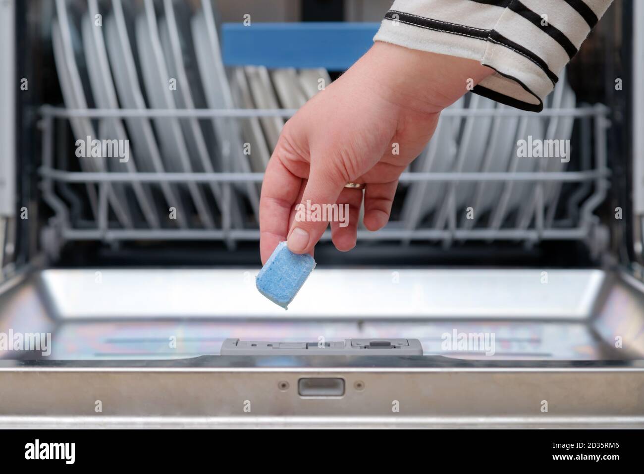 Close up of hand inserting soap capsule into dish washer in the kitchen
