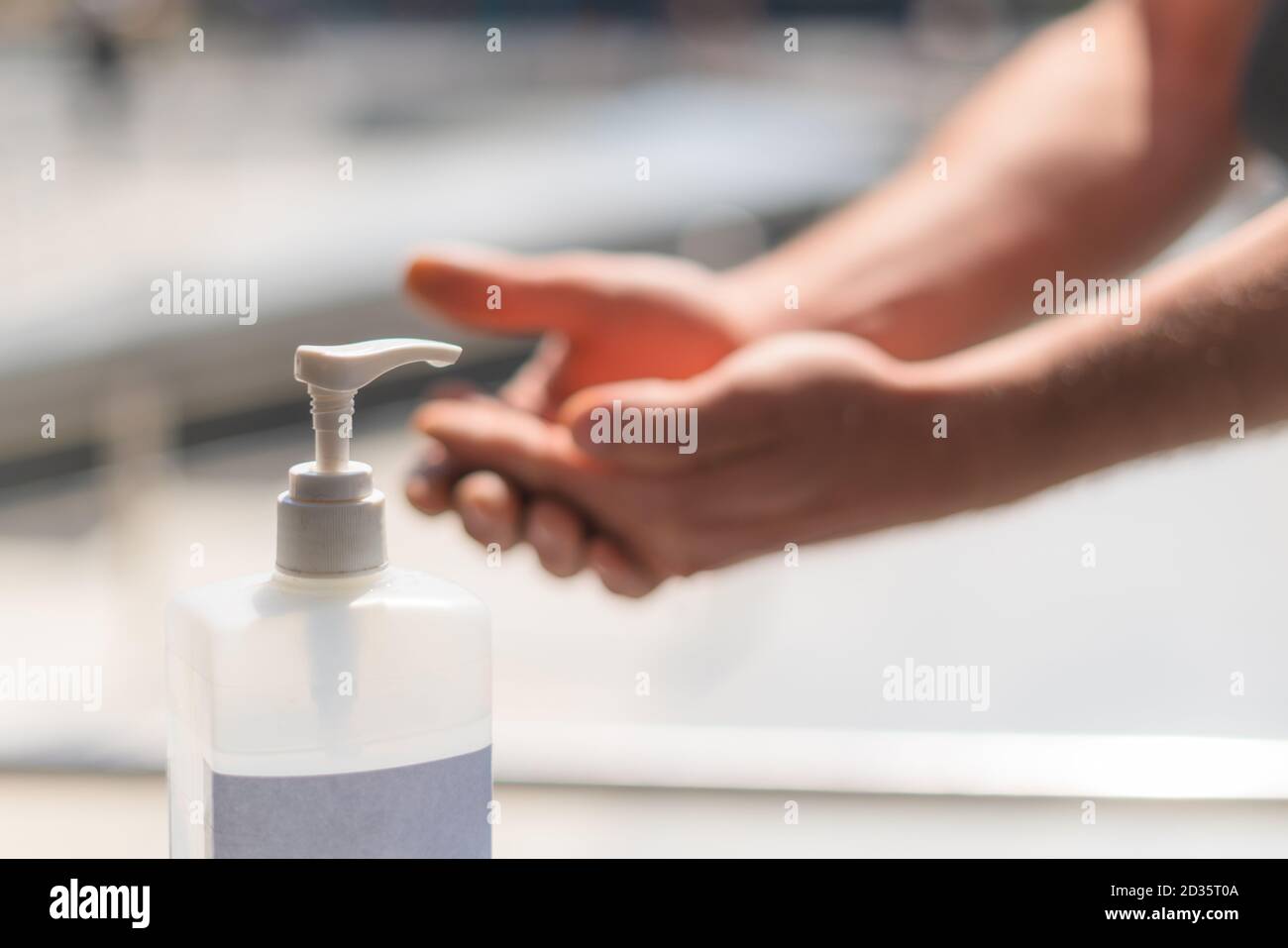 Person using hand sanitizer gel in public. Hand pressing antibacterial lotion bottle outside. Close up view of antiseptic being used in the street. Stock Photo