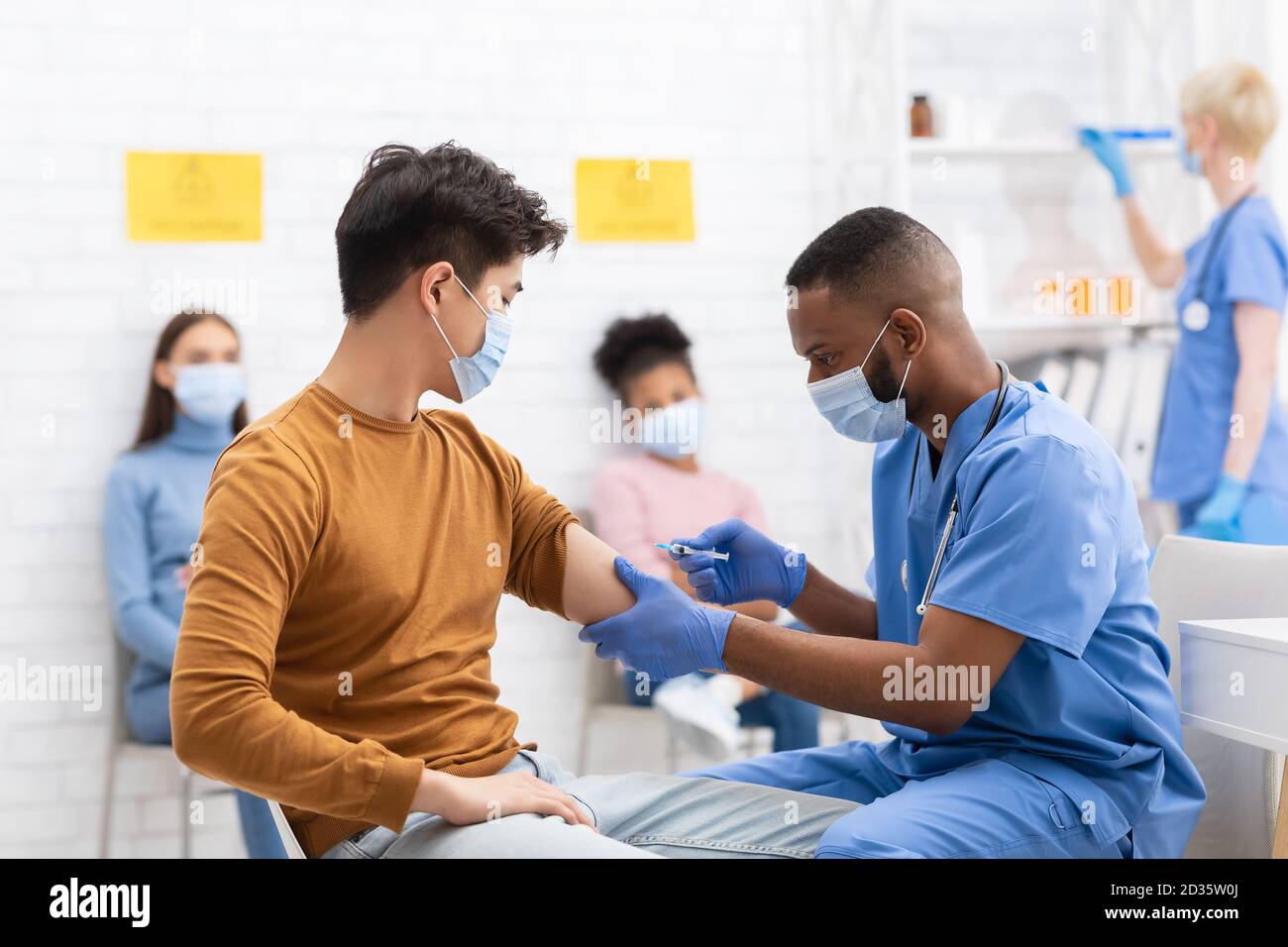Doctor Vaccinating Asian Male Patient Giving Covid-19 Vaccine In Hospital Stock Photo