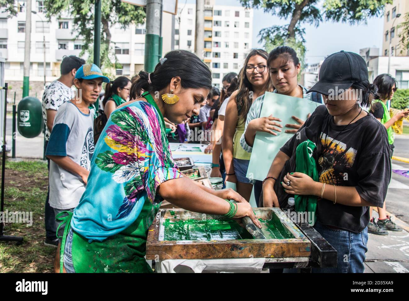 Woman printing slogans and designs on t-shirts and scarves for participants on the 2020 International Womens march in Lima, Peru Stock Photo