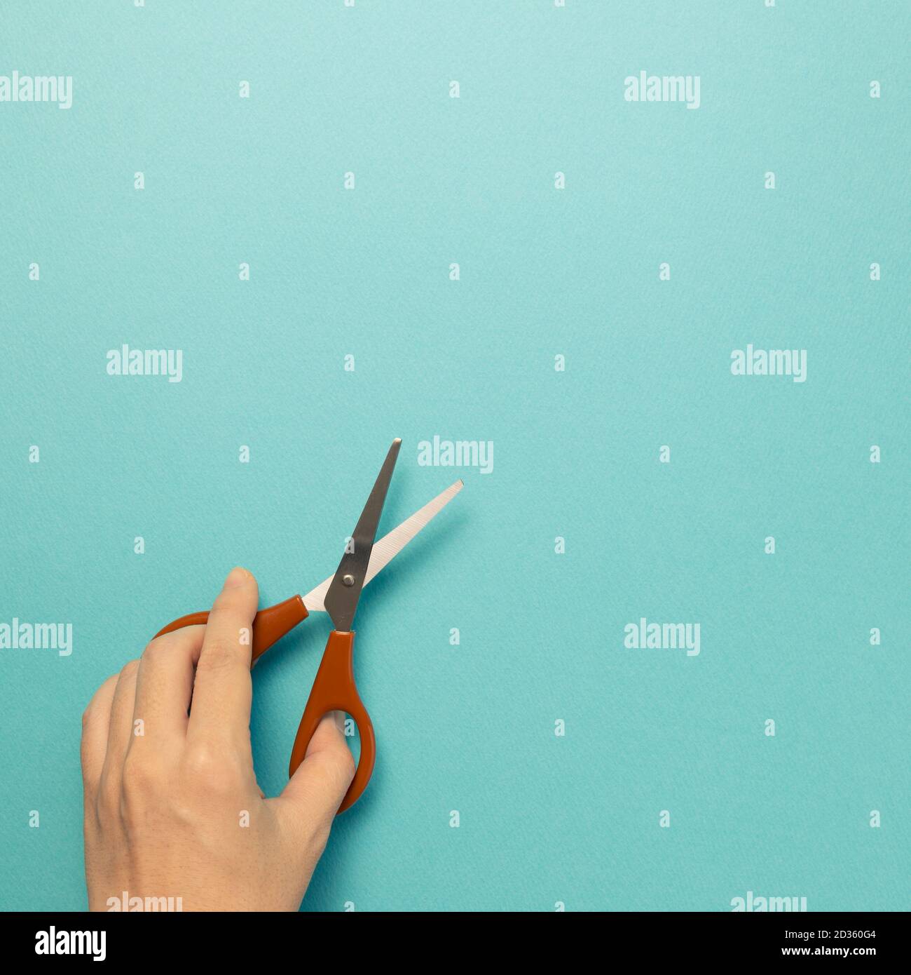 Scissors with hand on blue background. top view, copy space Stock Photo