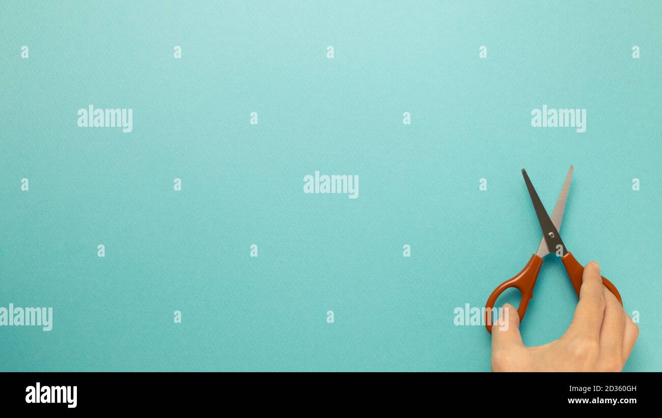 Scissors with hand on blue background. top view, copy space Stock Photo
