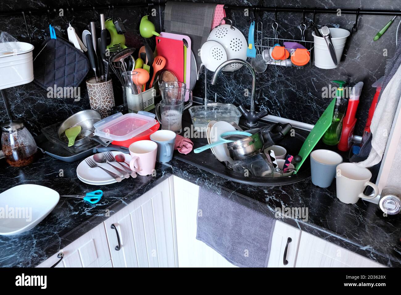 Dirty dishes in the kitchen sink and on the countertop. Not done household chores in the kitchen. A lot of dirty dishes after cooking. Stock Photo