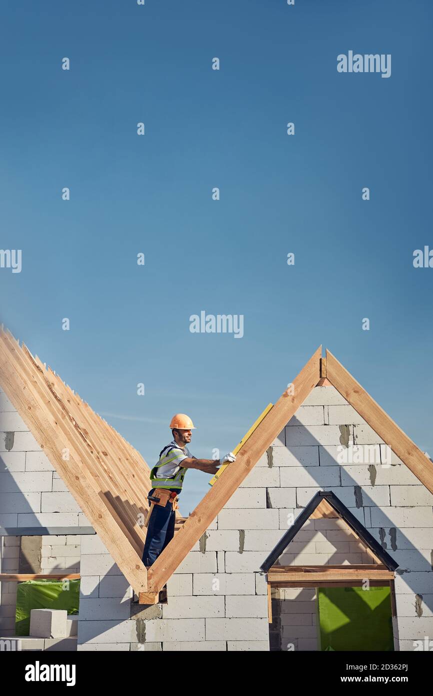 Experienced builder working on rooftop with a spirit level Stock Photo